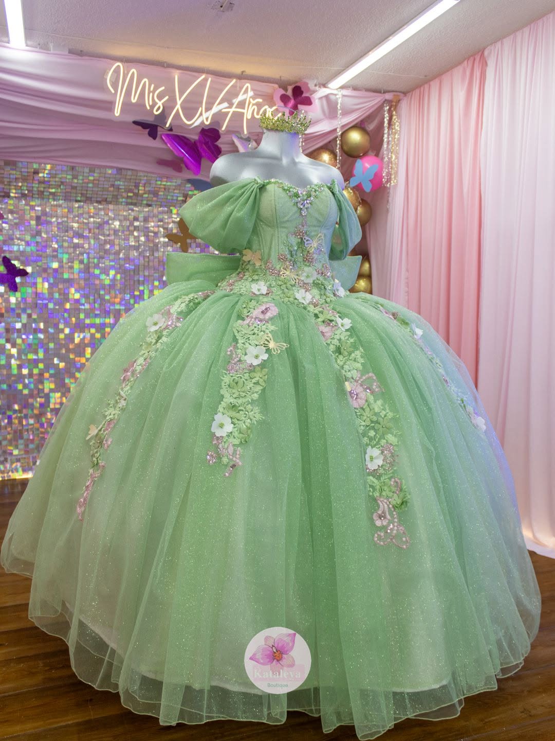 Vestido de XV años verde con flores y mariposas, en maniquí de Kataleya
